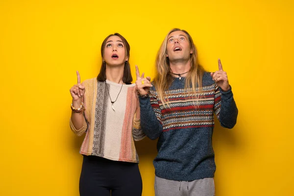 Hippi çift şaşırttı ve yukarı dönük sarı arka plan üzerinde