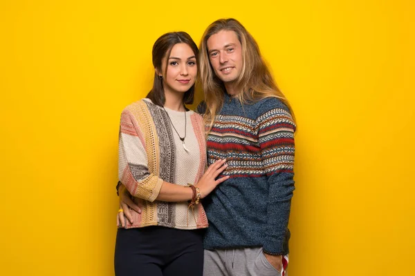 Hippi çift poz ve önüne bakarak gülen sarı arka plan üzerinde