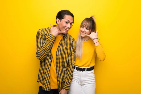 Junges Paar Auf Leuchtend Gelbem Hintergrund Mit Handygeste Rufen Sie — Stockfoto