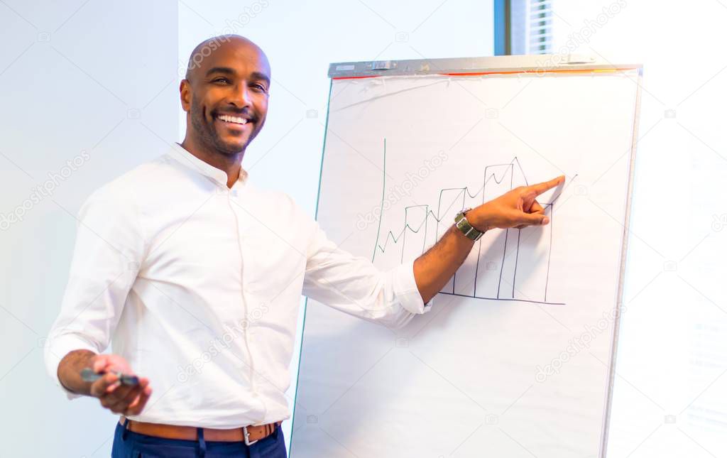 Young afro american businessman in the office writing on whiteboard a planning strategy