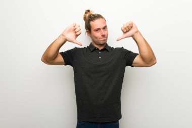 Başparmak aşağı her iki el ile gösterilen beyaz duvarın üzerinden uzun saçlı sarışın adam