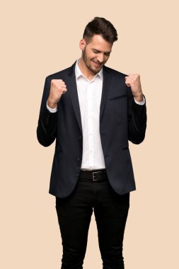 Koyu sarı arka plan üzerinde bir zafer kutluyor yakışıklı iş adamı