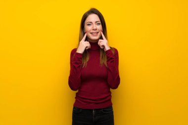 Balıkçı yaka mutlu ve keyifli bir ifadeyle gülümseyen sarı duvarın üzerinden kadınla