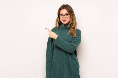 Ürün sunmak için genç kız tarafına işaret beyaz duvar üzerinde