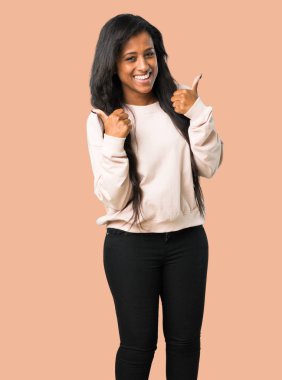 Her iki el ile jest Yaşasın vererek ve izole kahverengi zemin üzerinde gülümseyen genç afro Amerikalı kadın