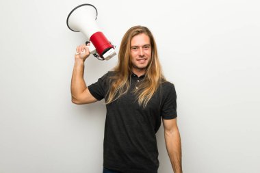 Beyaz duvar bir megafon holding üzerinden uzun saçlı sarışın adam