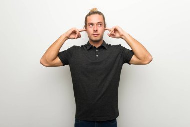 Beyaz duvar her iki kulak elleri ile kaplama üzerinde uzun saçlı sarışın adam