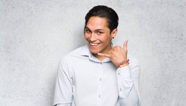 Yakışıklı adam telefon jesti yapıyor. Dokulu duvar arka planında bana geri tabela arayın