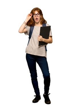 Gözlüklü ve izole beyaz arka plan üzerinde sürpriz bir genç redhead öğrenci tam uzunlukta bir kadeh