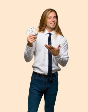 İzole arka plan üzerinde bir sürü para alarak uzun saçlı sarışın iş adamı