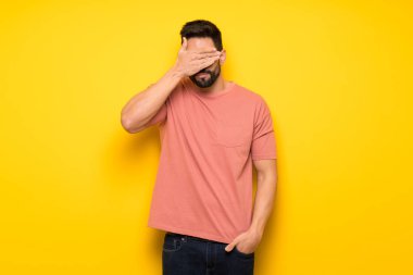 Sarı duvar eller tarafından gözleri kaplama yakışıklı adam. Bir şey görmek istiyor musunuz