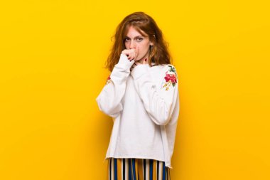 Genç Kızıl saçlı kadın sarı duvarın üzerinden öksürük ile acı ve kötü hissediyor