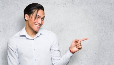 Yakışıklı adam dokulu duvar arka plan üzerinde yanal pozisyonda yan parmak işaret