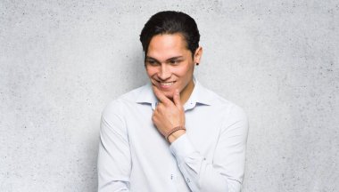 Yakışıklı adam dokulu duvar arka plan üzerinde çene üzerinde el ile yan bakıyor