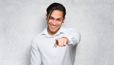 Yakışıklı adam dokulu duvar arka planda kendine güvenen bir ifade ile parmak işaret