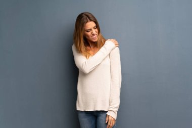 Bir çaba yapılmış olması için omuz ağrısı muzdarip gri arka plan üzerinde sarışın kadın