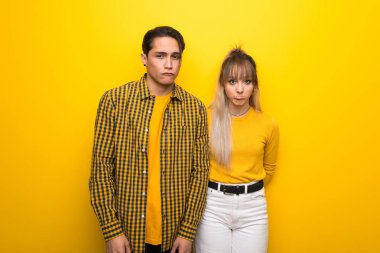 Üzgün ve depresif ifade ile canlı sarı arka plan üzerinde Genç çift