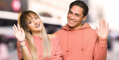 Genç çift şehirde mutlu ifade ile el ile selamlama