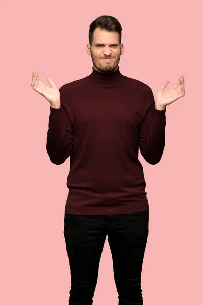不幸なタートルネックのセーターと男のためピンクの背景の上に何かを理解していません — ストック写真