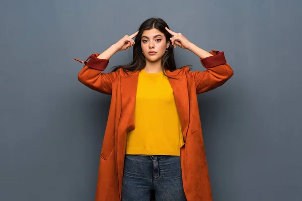 Adolescente Chica Con Abrigo Sobre Gris Pared Teniendo Dudas Pensando — Foto de Stock