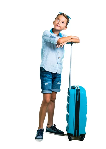全身带着太阳镜和耳机的孩子带着他的行李箱支架旅行 抬头看着孤立的白色背景 — 图库照片