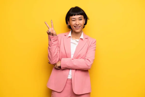 ピンクのビジネスと現代の女性に合う笑顔と示す勝利のサイン — ストック写真