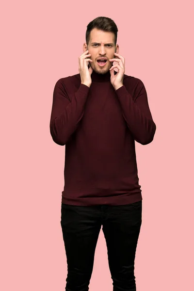 緊張感と恐怖のピンクの背景の前面に手の伸びるタートルネックのセーターを持つ男 — ストック写真
