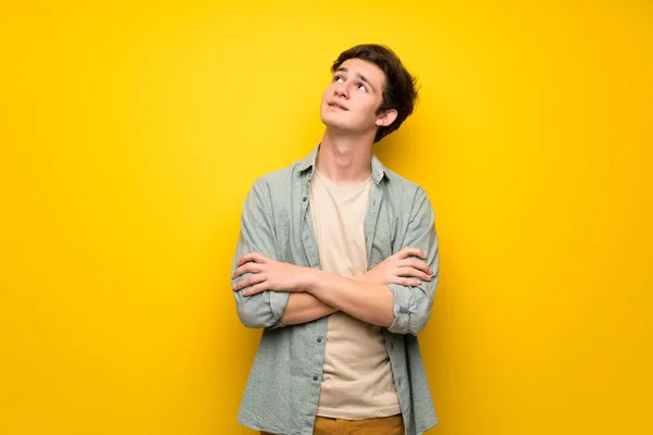 Mężczyzna Nastolatek Żółtej Ścianie Patrząc Jednocześnie Uśmiechając Się — Zdjęcie stockowe