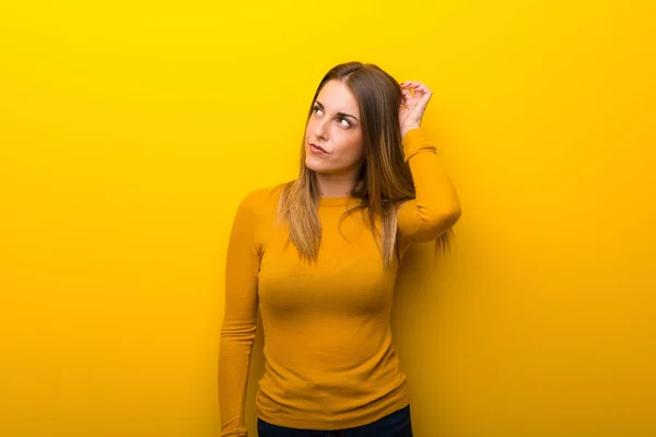 Young Woman Yellow Background Having Doubts While Scratching Head — Stock Photo, Image