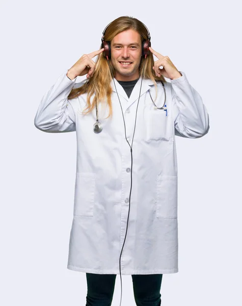 孤立した背景の上にヘッドフォンで音楽を聴く医師男 — ストック写真