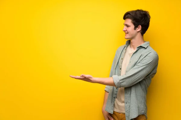 Dospívající Muž Nad Žluté Zdi Představování Myšlenky Zatímco Vypadající Úsměvem — Stock fotografie