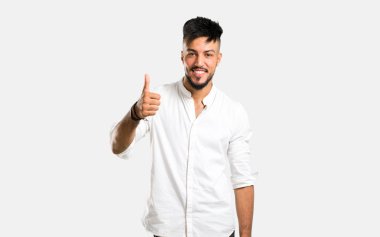 Beyaz gömlekli Arap genç adam. Gri arka planda gülümsüyor.