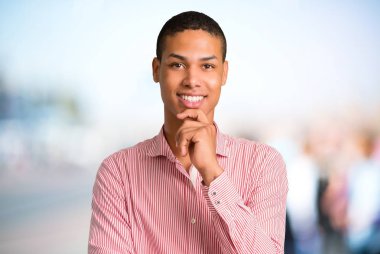 Gülümseyen ve öne doğru emin suratla odaklanmamış açık arka plan üzerinde seyir genç Afro-Amerikan adam