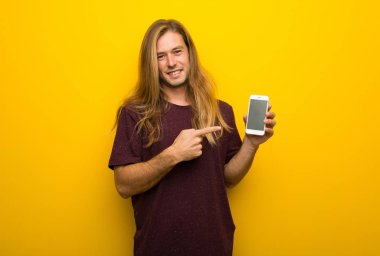 Belgili tanımlık hareket eden gösterilen sarı duvarın üzerinden uzun saçlı sarışın adam