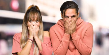 Şehirde ağız larını kapatan genç çift çok gülümsüyor