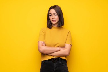 Genç kadın ile karıştırmayın yüz ifadesi ısırıkları dudak iken sarı duvarın üzerinden