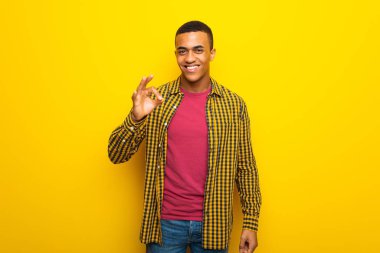 Parmaklar ok işaretiyle gösterilen sarı zemin üzerine genç afro Amerikalı adam