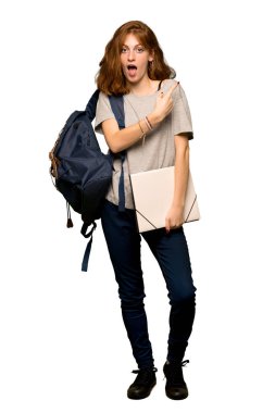 Bir sürpriz bir genç redhead öğrencinin tam uzunlukta atış ve işaret yan izole beyaz arka plan üzerinde