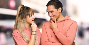 Genç çift şehirde çene üzerinde el ile yan bakıyor