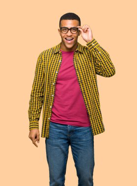 Genç afro Amerikalı adam gözlüklü ve sürpriz izole arka plan üzerinde