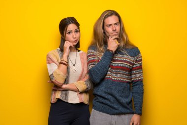 Hippi çift gülümseyen ve öne doğru emin yüz ile seyir sarı arka plan üzerinde