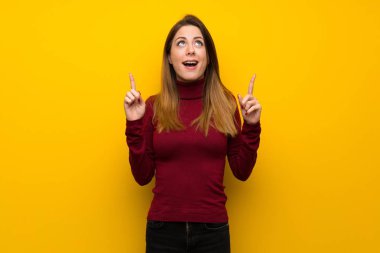 Kadın sarı duvar işaret üzerinde balıkçı yaka yukarı ve şaşırmış ile