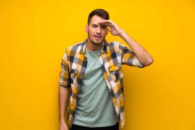 Bir şey bakmak için yakışıklı adam sarı duvar uzakta el ile seyir üzerinde