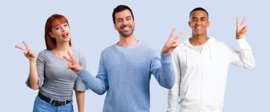 Grup gülümseyen ve zafer işaret gösteren üç arkadaşıyla