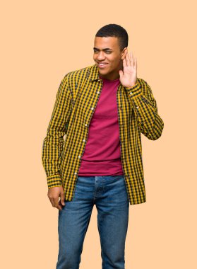 Genç afro Amerikalı adam için bir şey kulak yalıtılmış zemin üzerine elini koyarak dinleme