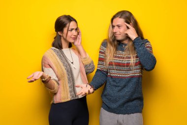 Hippi çift parmak kafasına koyarak delilik jest yaparak sarı arka plan üzerinde