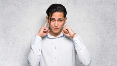 Dokulu duvar arka planda elleri ile her iki kulak kapsayan yakışıklı adam