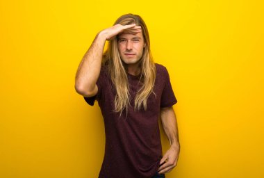 Sarı duvar uzakta el ile seyir üzerinde uzun saçlı sarışın adam bir şey bakmak için