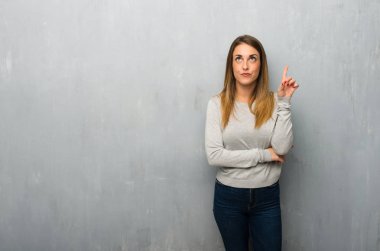 Genç kadın parmağı yukarıyı bir fikir düşünce dokulu duvar