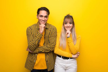 Canlı sarı arka plan üzerinde genç çift gülümseyerek ve kendinden emin bir yüz ile ön bakıyor